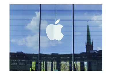 Apple logo in the all glass window.  City skyline reflection in the background.