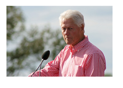 Former president Bill Clinton during an outdoor speach - Wearing a red and white checkered shirt - Year 2014