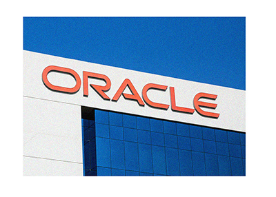 The Oracle company logo on top of a building.  The sky behind is clear.