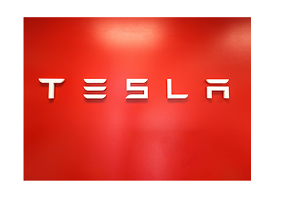 Tesla logo in a showroom.  Red background.  The year is 2018.